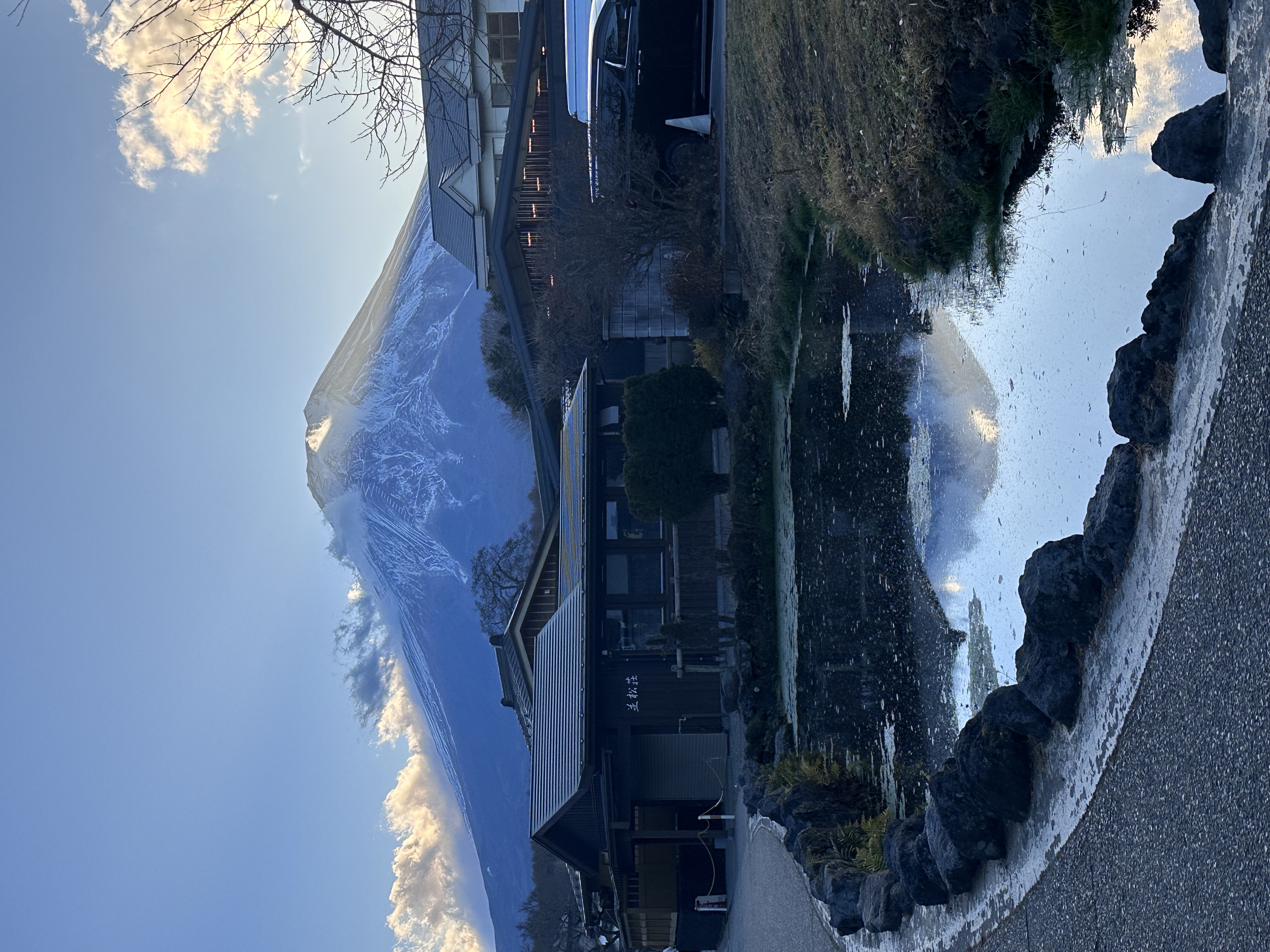 Snow-capped Mount Fuji above traditional rooftops and a reflective pond