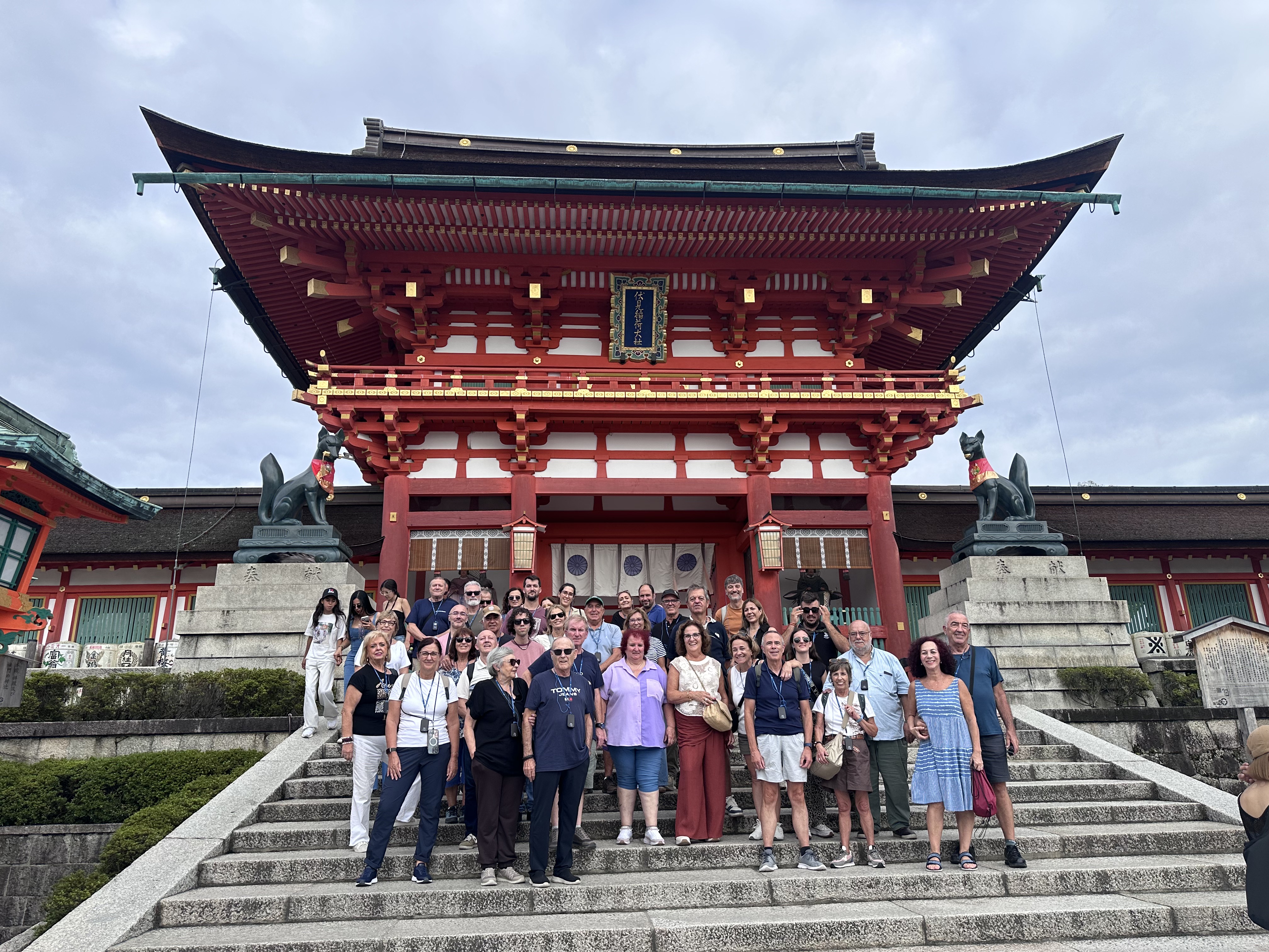 Travelers together on the steps in front of a vermilion shrine gate