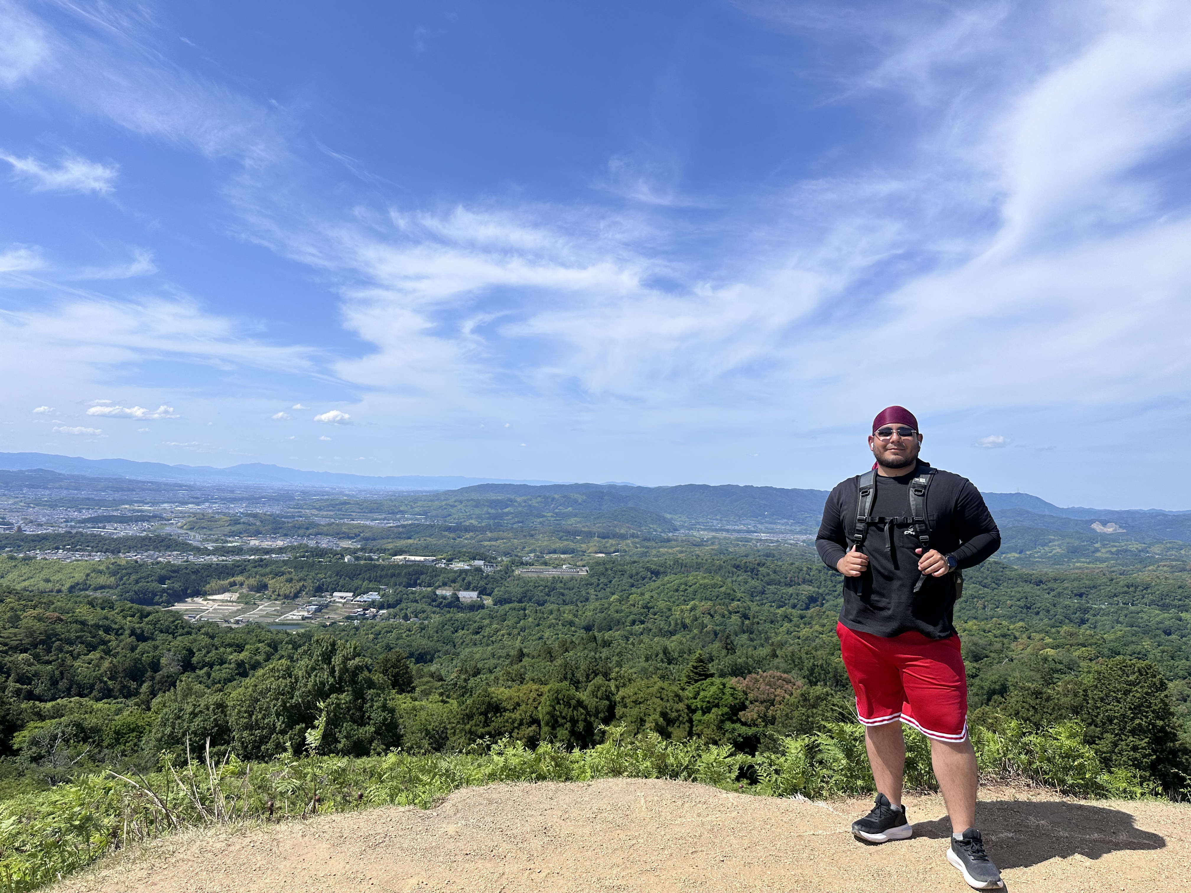 Eric hiking at a viewpoint overlooking green hills