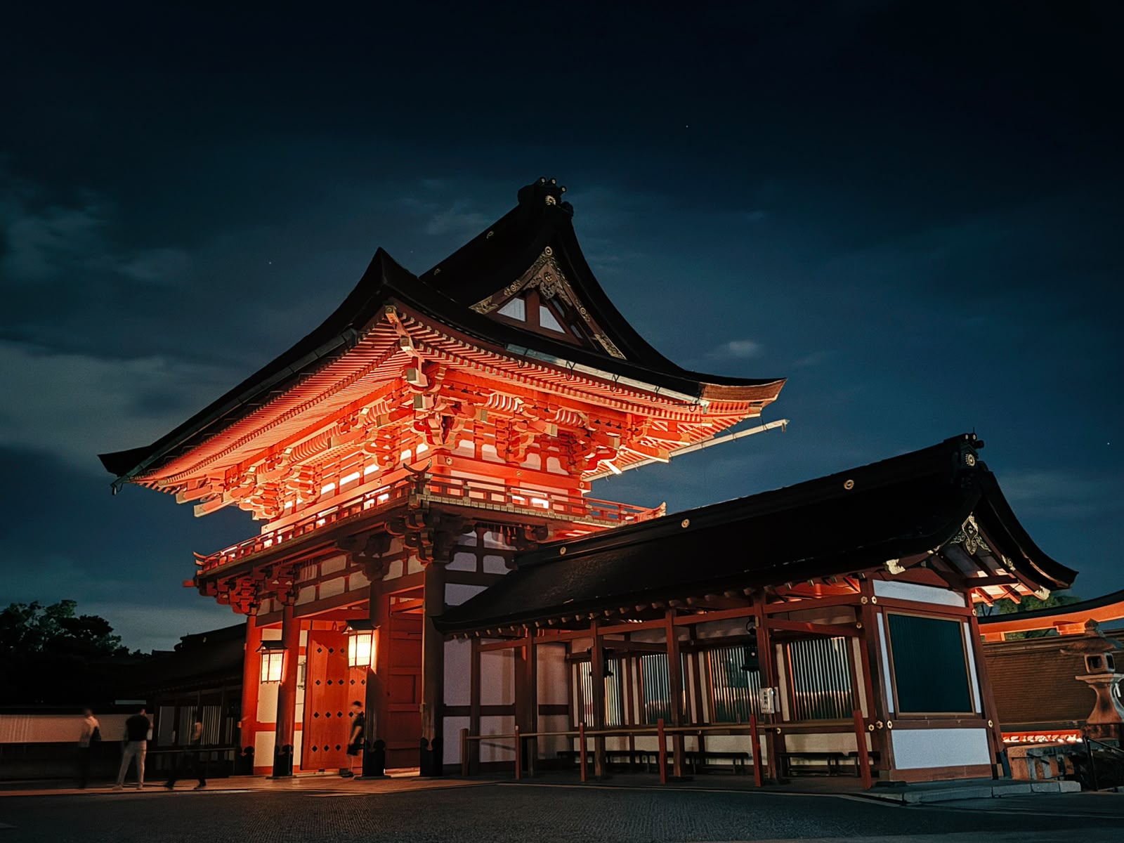 A vermilion shrine gate illuminated against the night sky